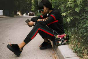 woman sitting on gray concrete sidewalk taken