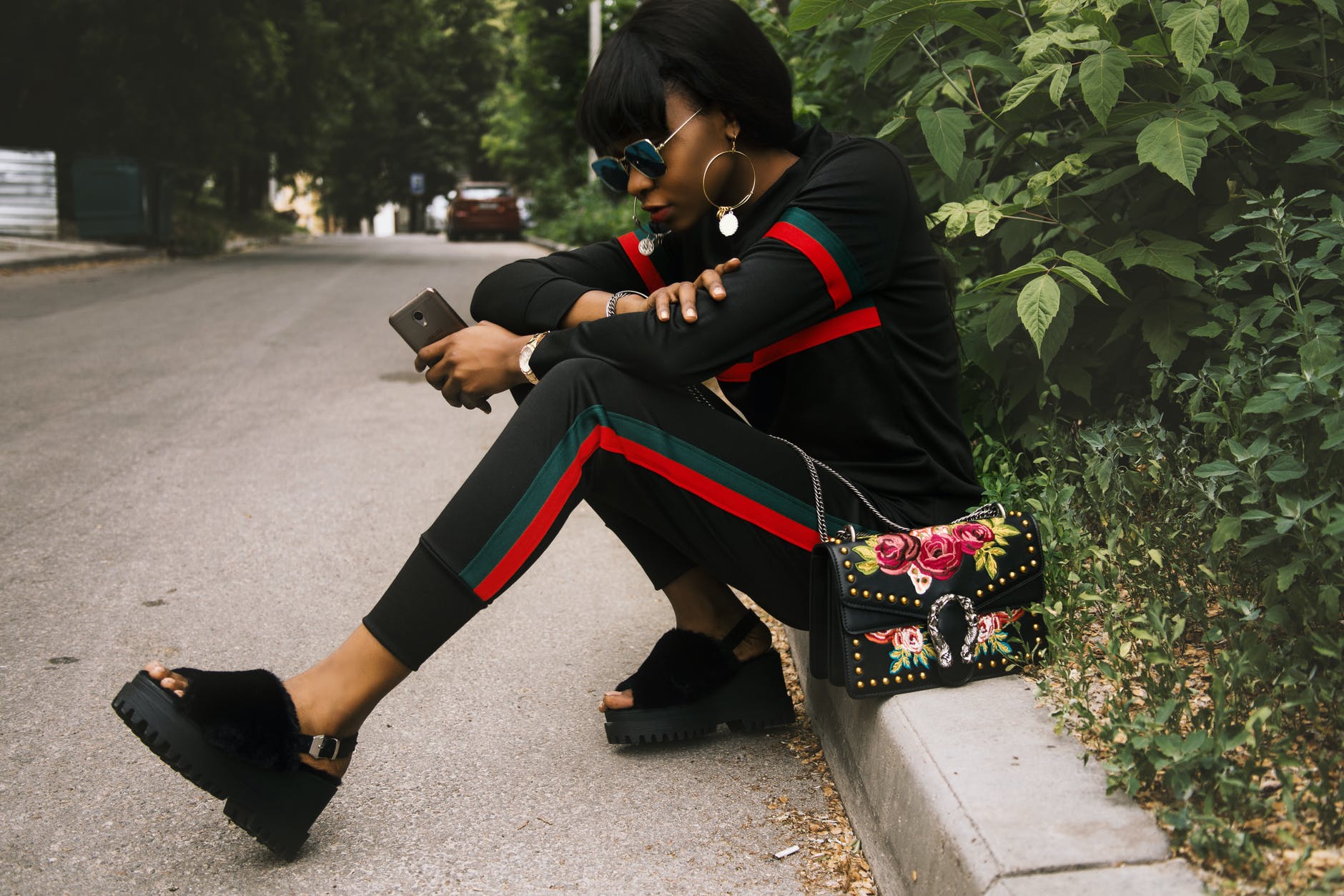 woman sitting on gray concrete sidewalk taken