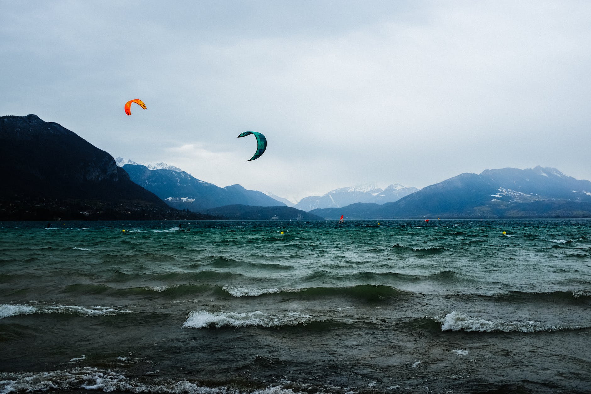 wavy ocean behind spectacular mountains and flying parachutes in evening